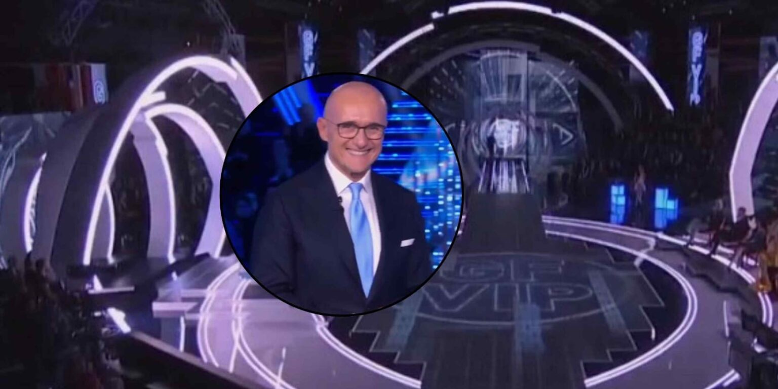Logo luminoso del Grande Fratello VIP con luci rosse e blu sullo sfondo e Alfonso Signorini